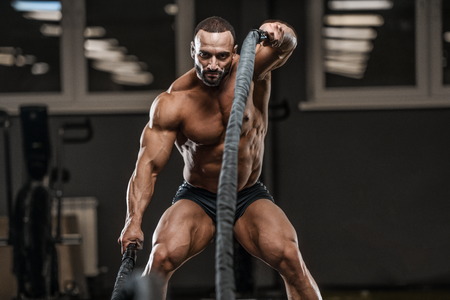 Brutal strong bodybuilder athletic man pumping up muscles workout bodybuilding concept background -...