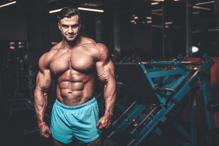 Handsome young fit muscular caucasian man of model appearance workout training in the gym gaining weight pumping up muscle, poses, drinks water  fitness and bodybuilding sport nutrition conceptの写真素材