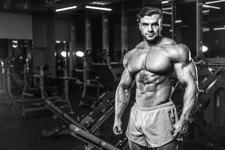 Handsome young fit muscular caucasian man of model appearance workout training in the gym gaining...