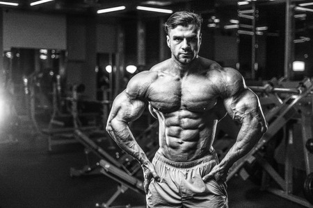 Handsome young fit muscular caucasian man of model appearance workout training in the gym gaining weight pumping up muscle, poses, drinks water  fitness and bodybuilding sport nutrition conceptの写真素材