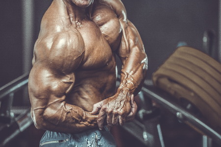 Brutal strong bodybuilder athletic aged man pumping up muscles workout bodybuilding concept background - muscular bodybuilder handsome men doing exercises in gym naked torso sport and diet conceptの写真素材