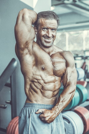 Brutal strong bodybuilder athletic aged man pumping up muscles workout bodybuilding concept background - muscular bodybuilder handsome men doing exercises in gym naked torso sport and diet conceptの写真素材