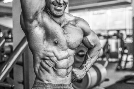 Brutal strong bodybuilder athletic aged man pumping up muscles workout bodybuilding concept background - muscular bodybuilder handsome men doing exercises in gym naked torso sport and diet conceptの写真素材