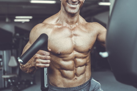 Brutal strong bodybuilder athletic aged man pumping up muscles workout bodybuilding concept background - muscular bodybuilder handsome men doing exercises in gym naked torso sport and diet conceptの写真素材