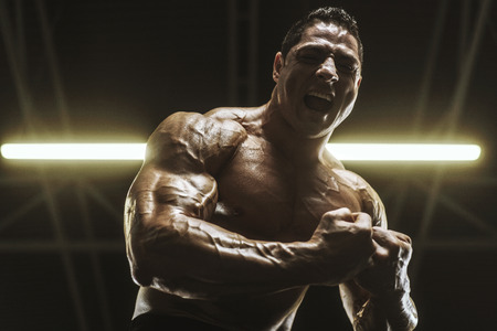 Handsome strong athletic men pumping up muscles workout bodybuilding concept background - muscular bodybuilder handsome men doing exercises in gym naked torsoの写真素材