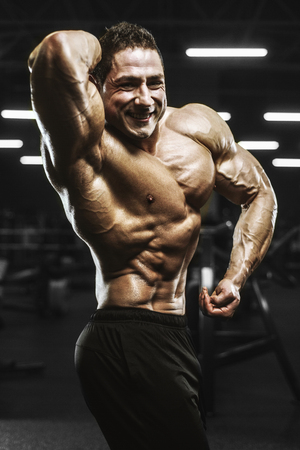 Handsome strong athletic men pumping up muscles workout bodybuilding concept background - muscular bodybuilder handsome men doing exercises in gym naked torsoの写真素材