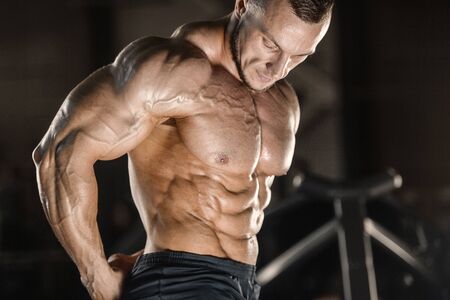 Handsome strong athletic men pumping up muscles workout fitness and bodybuilding concept background - muscular bodybuilder fitness men doing abs exercises in gym naked torsoの写真素材