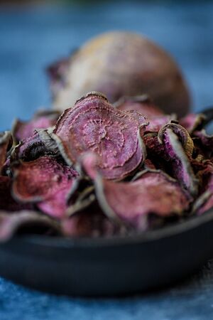 vegetarian pile of healthy beet chips Purple Baked Beet Chips Vegan snacks, vegetable chips in canvas bag and ceramic bowl, rustic still life, selective focusの写真素材
