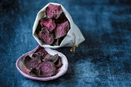 vegetarian pile of healthy beet chips Purple Baked Beet Chips Vegan snacks, vegetable chips in canvas bag and ceramic bowl, rustic still life, selective focusの写真素材