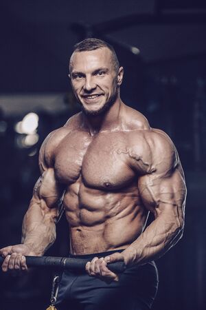 Brutal strong athletic men pumping up muscles workout bodybuilding concept background - muscular bodybuilder handsome men doing exercises in gym naked torsoの写真素材