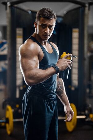 Sport muscular fitness man drinking water after workout cross fitness and bodybuilding concept gym background abs muscle exercises in gym naked torso fitness conceptの写真素材
