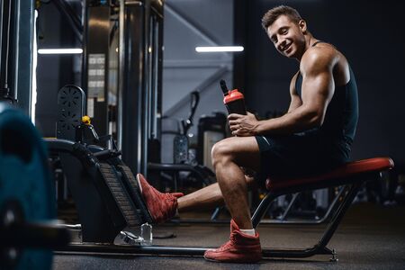 Sport muscular fitness man drinking water after workout cross fitness and bodybuilding concept gym background abs muscle exercises in gym naked torso fitness conceptの写真素材