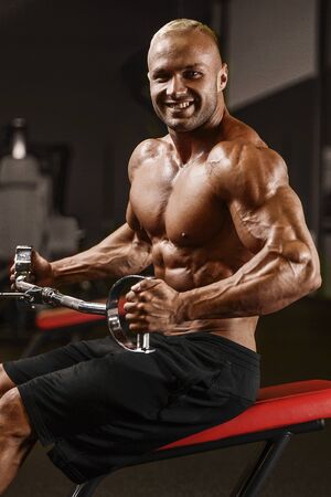 Handsome strong athletic man pumping up muscles workout fitness and bodybuilding concept background - muscular bodybuilder fitness men doing arms abs back exercises in gym naked torsoの写真素材