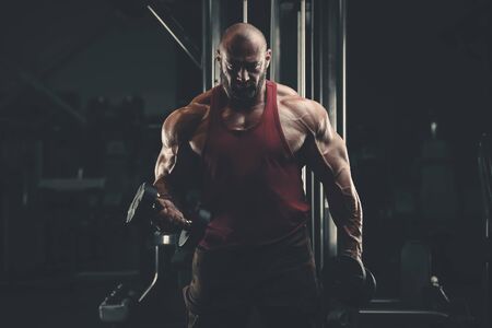 Bodybuilder handsome strong athletic man pumping up biceps muscles workout fitness and bodybuilding concept background - muscular fitness men doing arms exercises in gym naked torsoの写真素材