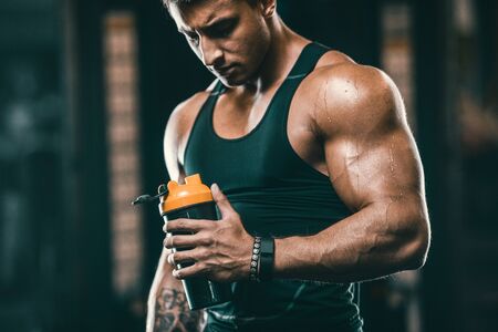 Sport muscular fitness man drinking water after workout cross fitness and bodybuilding concept gym background abs muscle exercises in gym naked torso fitness conceptの写真素材