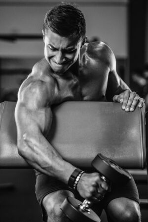 Handsome strong athletic men pumping up biceps muscles workout fitness and bodybuilding concept background - muscular bodybuilder fitness men doing arms exercises in gym naked torsoの写真素材