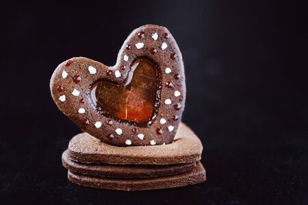 Stacked heart shaped cookies dark background isolated gluten-free caramel ginger biscuits. Saint Valentine's Day concept holiday greeting card. Romantic love dateの写真素材