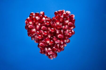 Red scarlet pomegranate seeds heart shape at isolated background fruit. Saint Valentine's Day concept holiday romantic love. Healthy food nutrition organic raw dietの写真素材