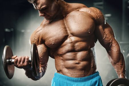 Bodybuilder handsome strong athletic rough man pumping up biceps muscles workout fitness and...