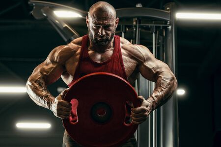 Bodybuilder handsome strong athletic rough man pumping up muscles workout fitness and bodybuilding healthy concept background - muscular fitness men doing arms exercises in gym naked torsoの写真素材