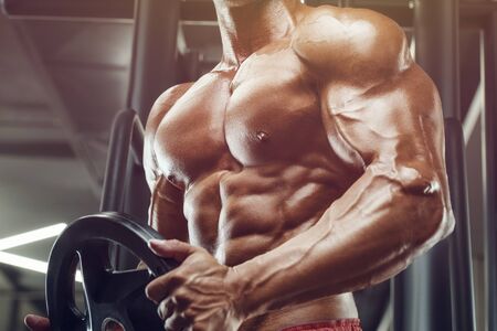 Bodybuilder handsome strong athletic rough man pumping up muscles workout fitness and bodybuilding healthy concept background - muscular fitness men doing arms exercises in gym naked torsoの写真素材