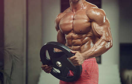 Bodybuilder handsome strong athletic rough man pumping up muscles workout fitness and bodybuilding healthy concept background - muscular fitness men doing arms exercises in gym naked torsoの写真素材