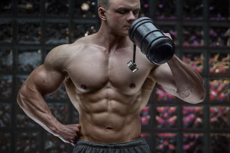 Fitness man in gym drinking water after workout looking at cell phone. Fitness and bodybuilding...