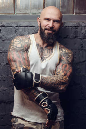 brutal tattooed fighter in fight club with punching bagの写真素材