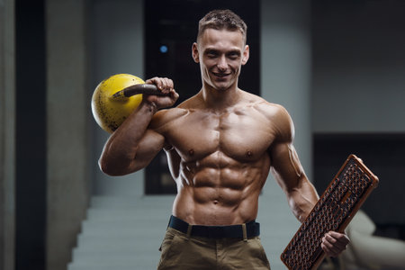 Fitness man at workout in gym pumping up muscles with kettlebell. Fitness and bodybuilding health care conceptの写真素材