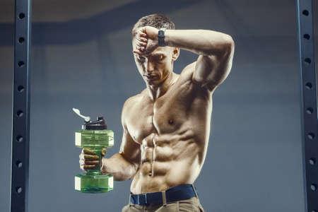 Caucasian fitness man drinking water after workout in gym. Fitness and bodybuilding healthy background. Nutrition and health care conceptの写真素材