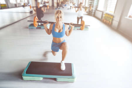 Beautiful strong sexy athletic muscular young caucasian fitness woman workout training in the gym on diet pumping up abs muscles and posing bodybuilding health care and fitness body bar conceptの写真素材