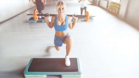 Beautiful strong sexy athletic muscular young caucasian fitness woman workout training in the gym on diet pumping up abs muscles and posing bodybuilding health care and fitness body bar conceptの写真素材