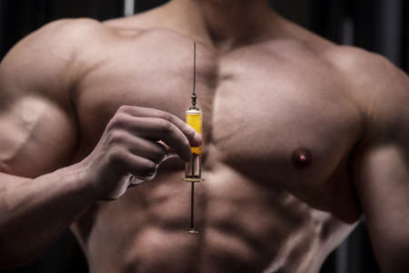 athlete holds a syringe, injector in front of him with a naked torso. Sport and vaccination medicine...