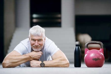 good looking gray haired senior man in white shirt with a water bottle. Sport and health care conceptの写真素材