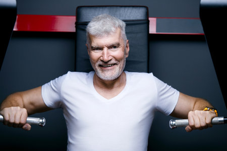 Handsome gray haired senior man at machine gym. Sport and health care concept