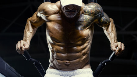Brutal and muscular strong bodybuilder athletic man pumping up muscles at workout in the gym. Sport and health care concept backgroundの写真素材