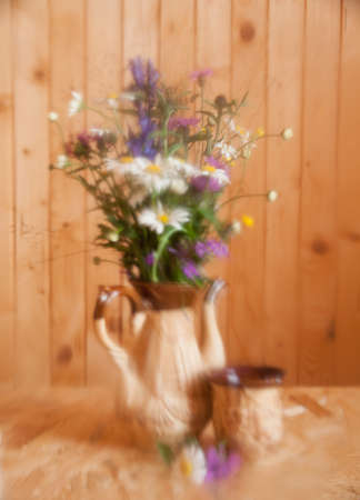 Bouquet of wild flowers on the background of a wooden wall. Still life  is photographed through  tarnished glass. Selective focus.の写真素材