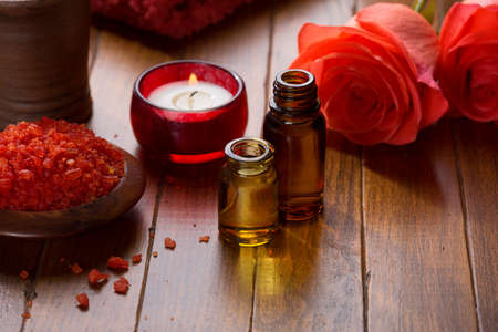 Essential oil, Mineral bath salts, candle and flowers on the brown  wooden table.の写真素材
