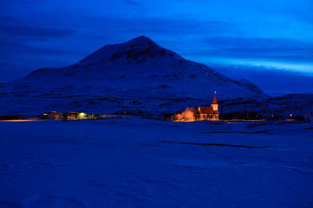 Icelandic winter landscape with church on the background of the mountains at dusk. near Akureyri, Icelandの写真素材