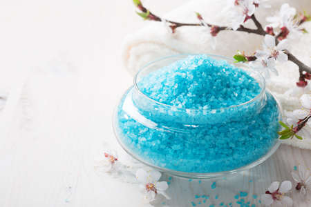 Mineral bath salts, , towels and flowers on the  wooden table. Shallow DOF. Focus on the salt.の写真素材