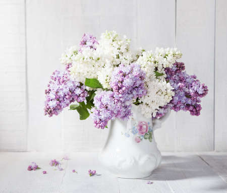 Lilac bouquet in ceramic jug against a white wooden walの写真素材