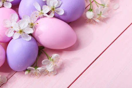 Easter eggs and  white flowers on  pink wooden table.の写真素材
