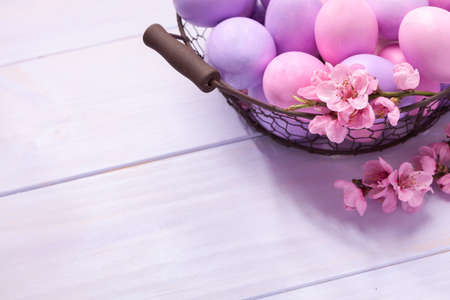 Easter eggs and   blooming peach branch on   wooden table. 
