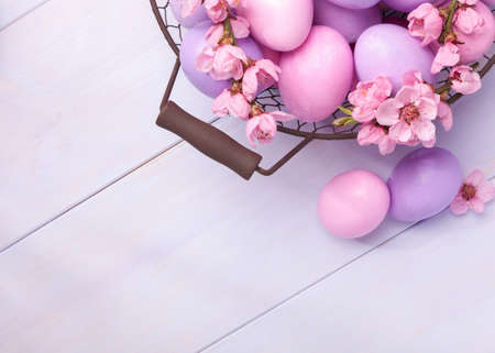 Easter eggs and   blooming peach branch on   wooden table. 