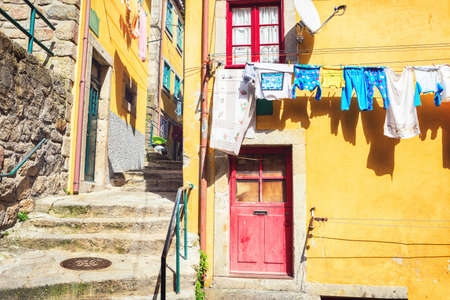 Colorful houses in a narrow street with hanging laundry, Ribeira district, Porto, Portugal.