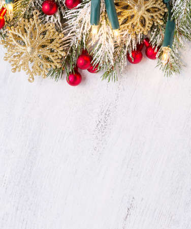 Fir branch with Christmas decorations and glowing garland on old wooden shabby background with empty space for text. Top view.の写真素材