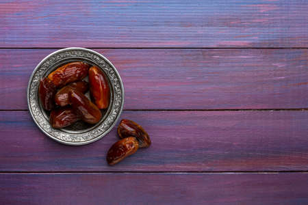 Plate of dates on dark violet wooden background. Flat lay.の写真素材