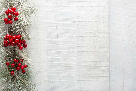 Winter background with fir branch and red berries on  old white  wooden board.  Christmas background with copy space for  text.  Flat lay composition.の写真素材