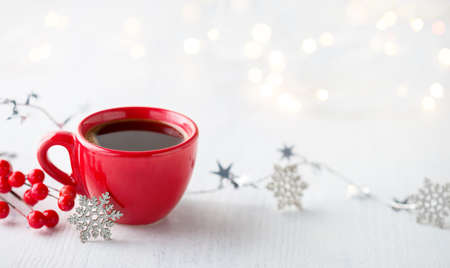 Red cup of coffee and Christmas decoration on white rustic wooden table. Shallow DOF. Selective...