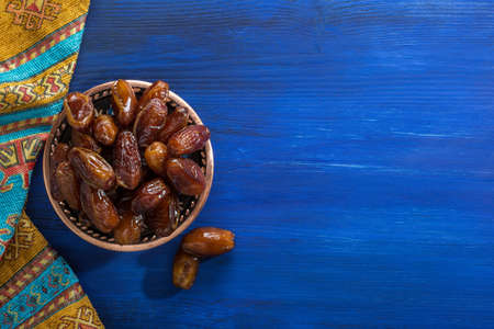 Bronze plate with dates on old blue wooden table.  Ramadan background.  Flat lay.